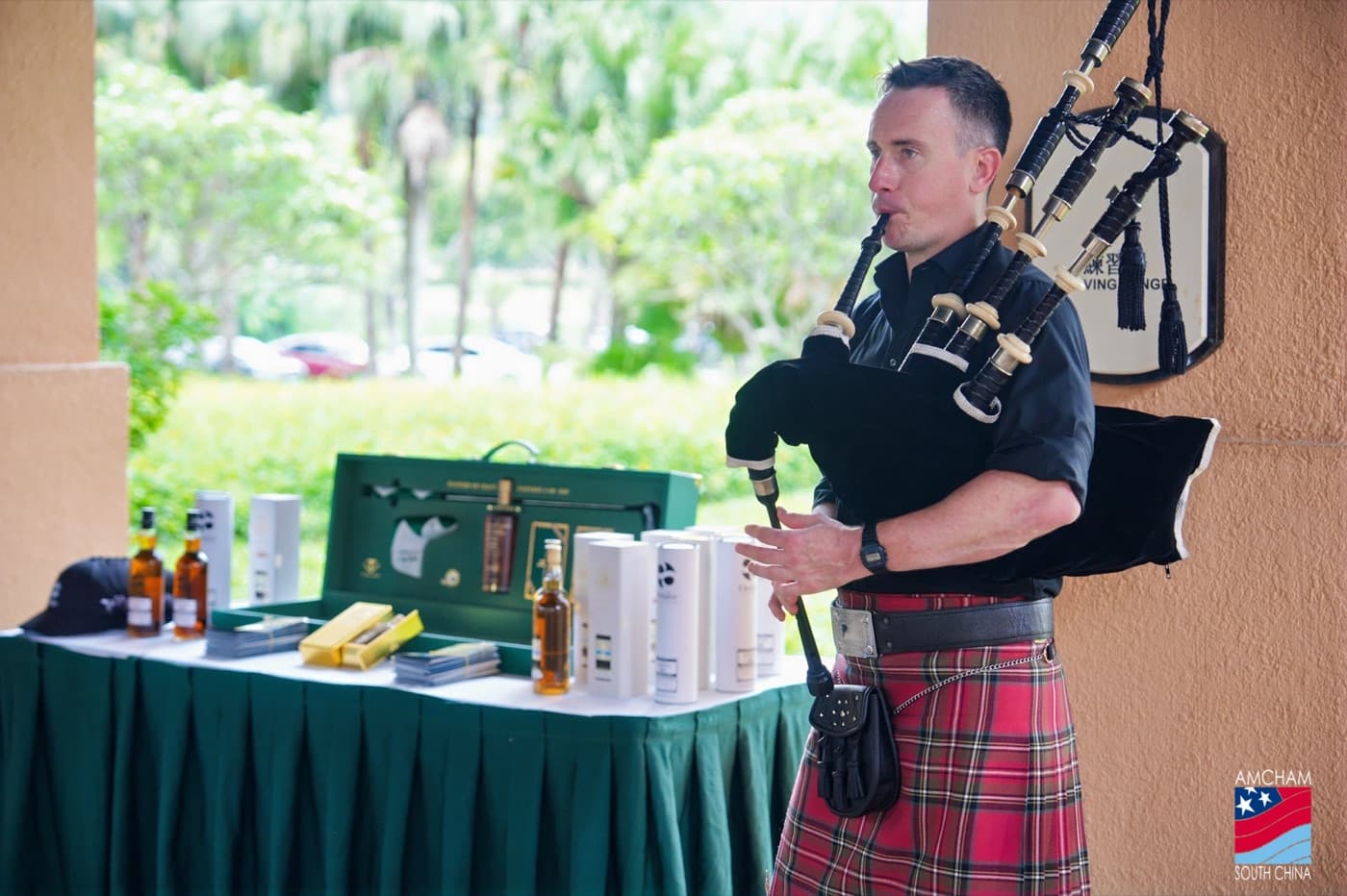 A kilted piper welcoming guests at an AGS whisky and golf event