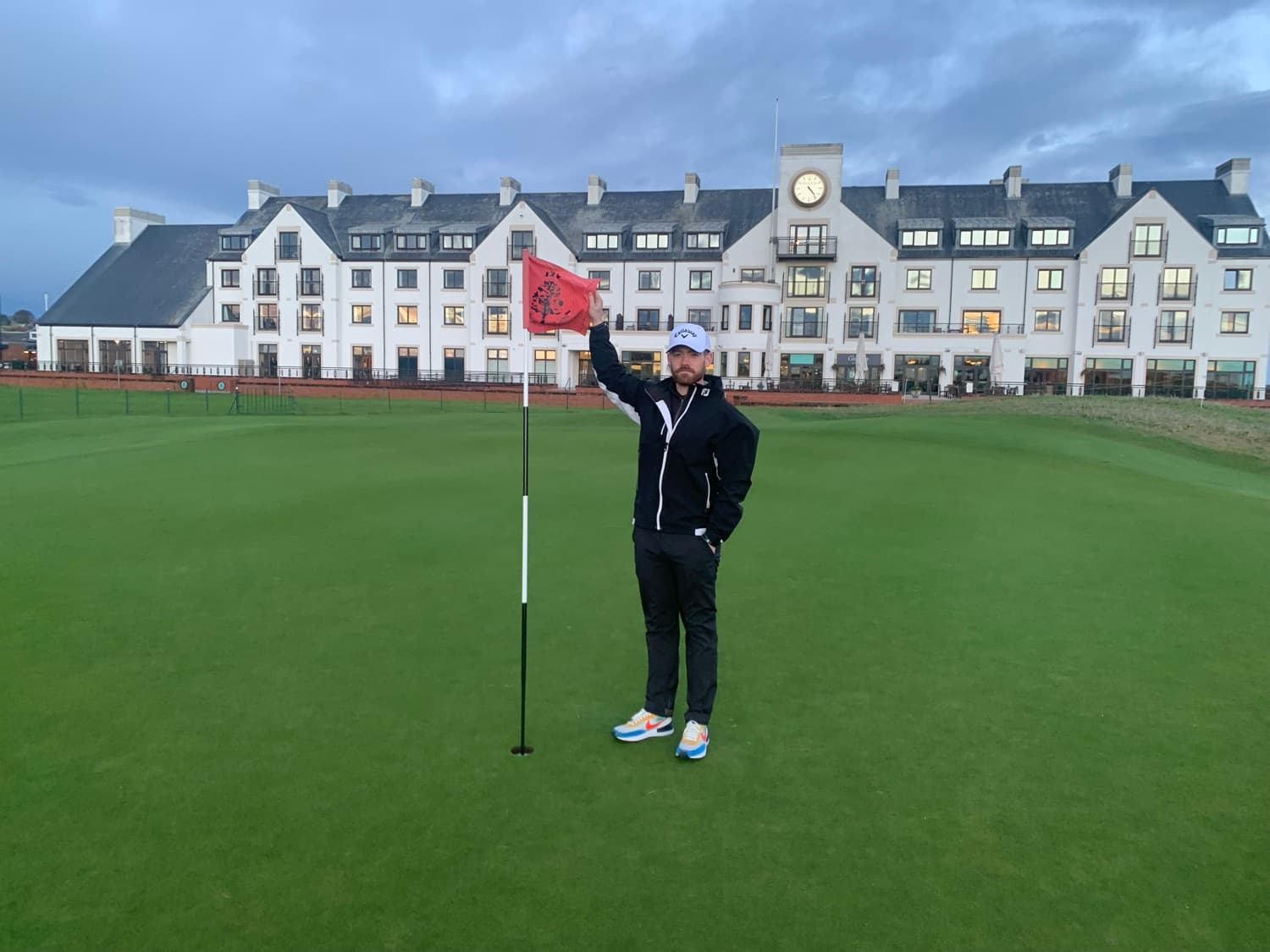 A golfer holding the flag at the Carnoustie clubhouse